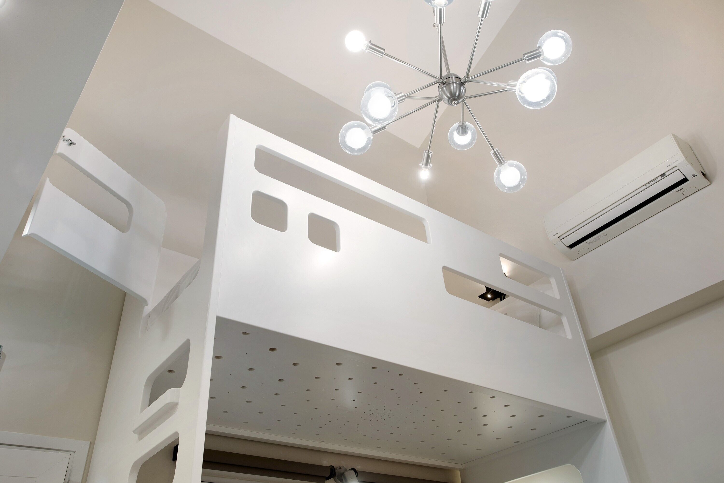 A room with a bunk bed, a ceiling light fixture, and an air conditioning unit.