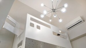 Una habitación con literas, una lámpara en el techo y un equipo de aire acondicionado.