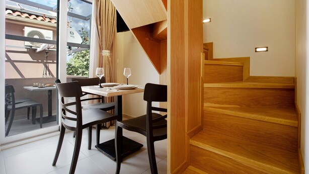 A dining area with a table and chairs, a staircase, and a view through a glass door. - Holiday Apartment "Casa Doppia 2" with Sea View, Balcony & Wi-Fi (Zakynthos)
