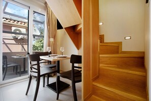A dining area with a table and chairs, a staircase, and a view through a glass door.