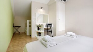A hotel room with a bed, a desk with a chair, a bookshelf, and an air conditioning unit. - Holiday Apartment "Casa Doppia 2" with Sea View, Balcony & Wi-Fi (Zakynthos)