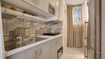 A modern kitchen with a stainless steel sink, a microwave, and a built-in oven.