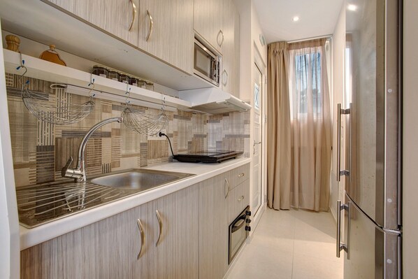 A modern kitchen with a stainless steel sink, a microwave, and a built-in oven.