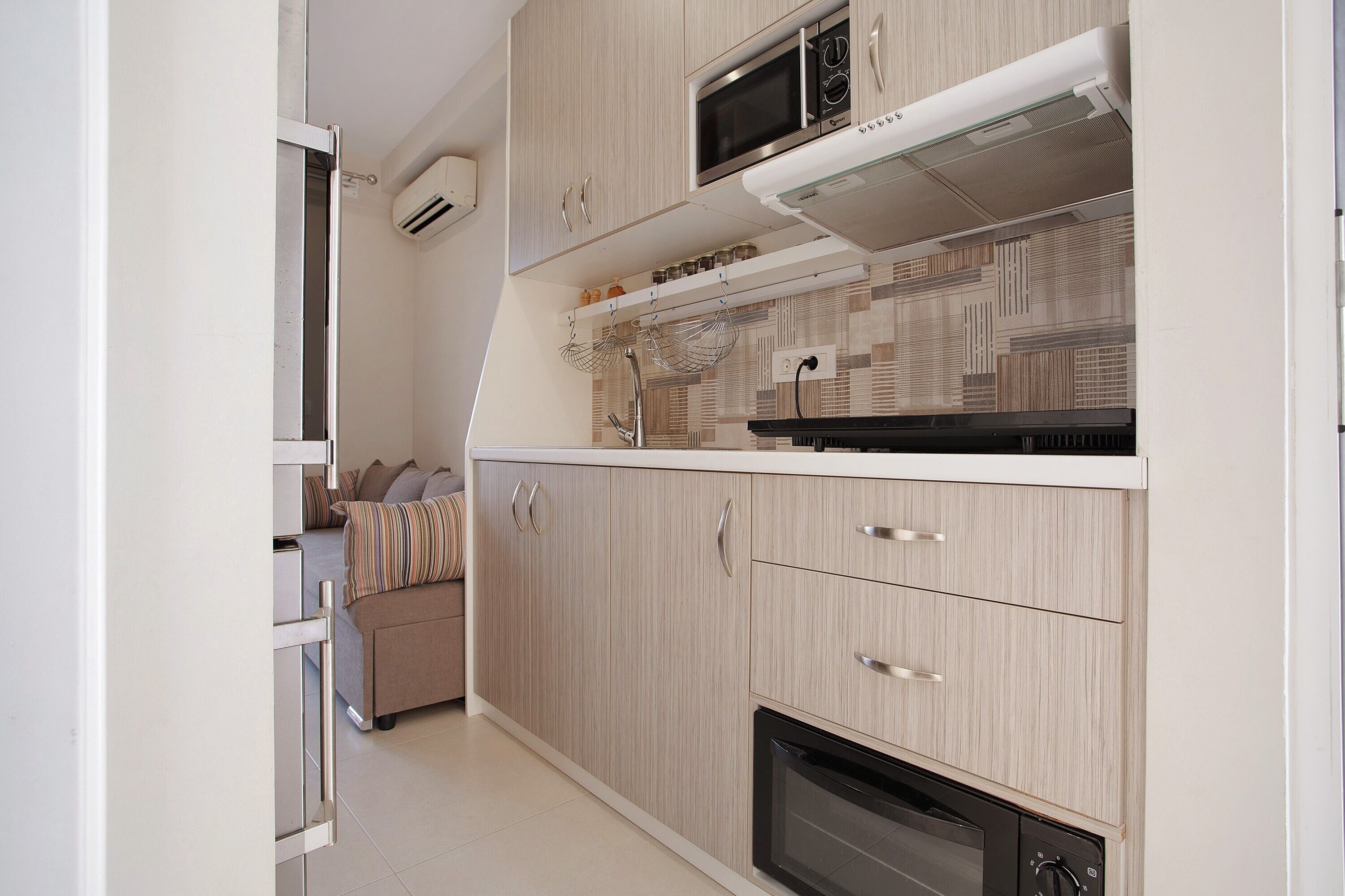 A compact kitchen with a microwave, oven, and a built-in range hood.