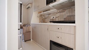 Cuina compacta amb microones, forn i campana extractora integrada.