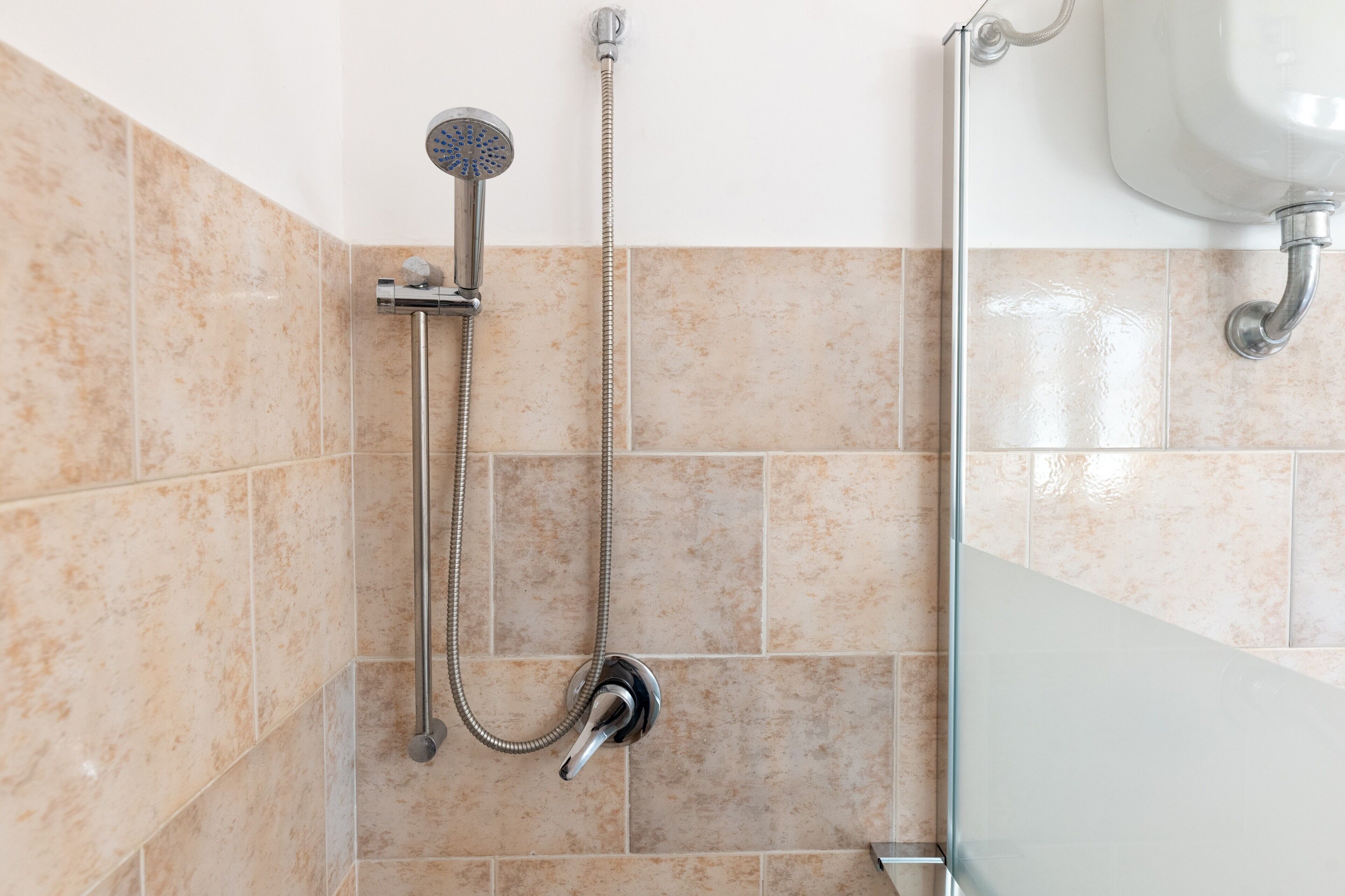 Ein Badezimmer mit Dusche, Waschbecken und Fliesen.