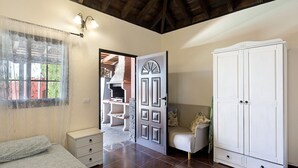 Een slaapkamer met een bed, een kledingkast, een deur en een raam met gordijnen.