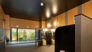 Un baño moderno con un espejo grande, una separación negra y un pequeño cubo de basura.