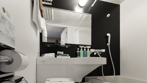 Un baño moderno con inodoro, lavabo y ducha. Hay artículos de aseo en el lavabo y un perchero sobre el inodoro.