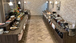 Un'impostazione buffet con diverse postazioni per il cibo, una parete in mattoni e un pavimento con motivo a spina di pesce.