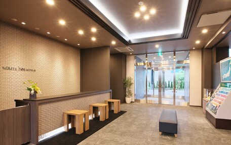 A hotel reception area with a brick wall, wooden reception desk, and a seating area with benches.
