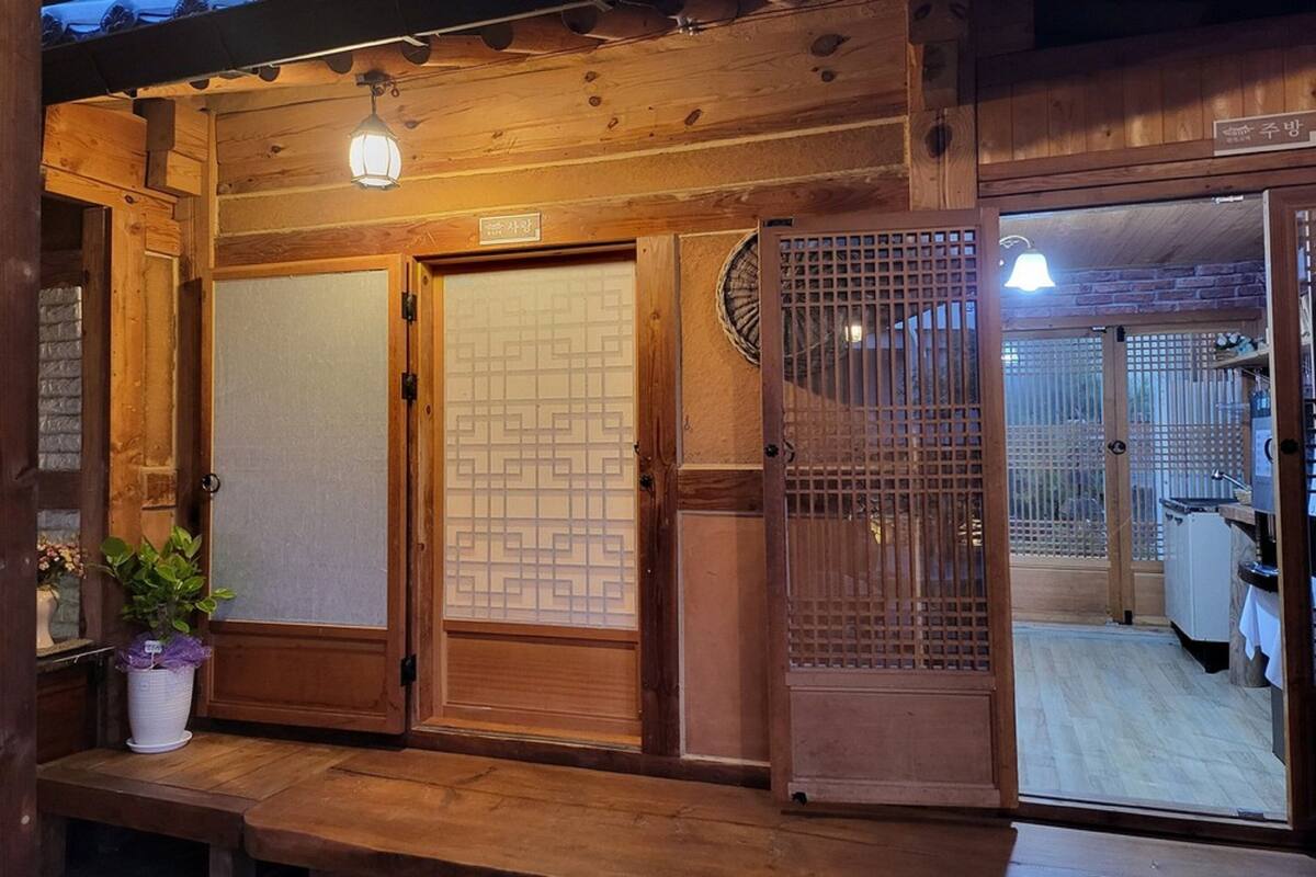 A traditional Japanese-style entrance with sliding doors, a wooden bench, and a potted plant.