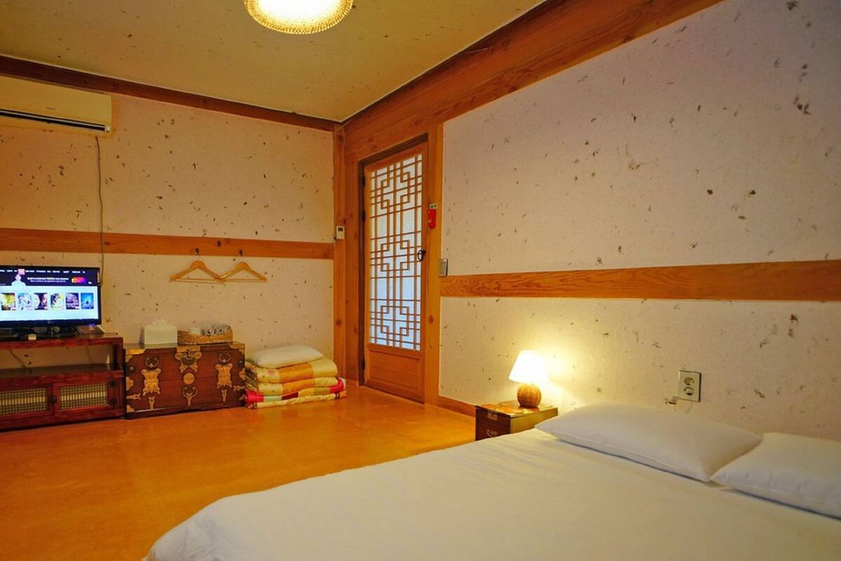 A hotel room with a bed, a television, a wooden cabinet, and a traditional Japanese sliding door.