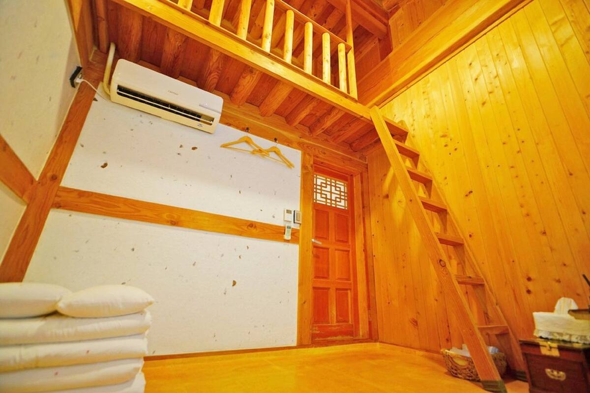 A wooden interior with a white air conditioning unit, a wooden door, and a staircase.