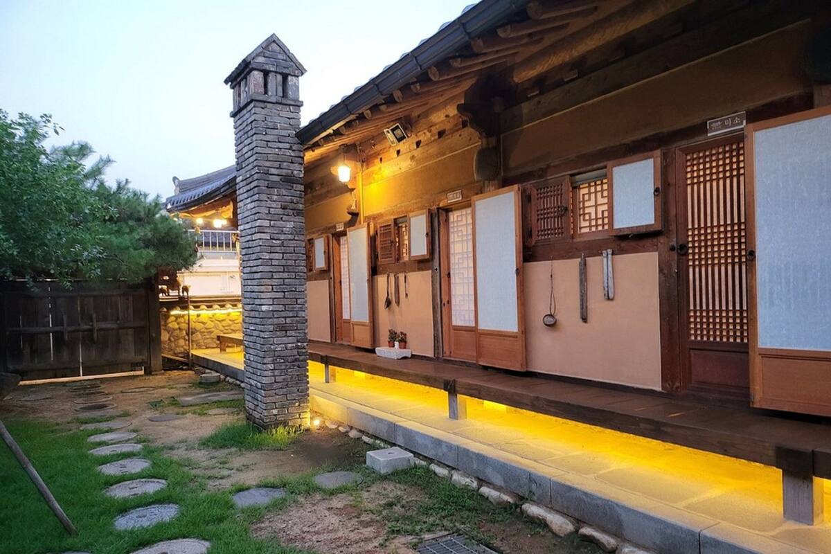 A traditional Japanese-style building with a stone chimney, wooden doors, and a stone pathway leading to the entrance.