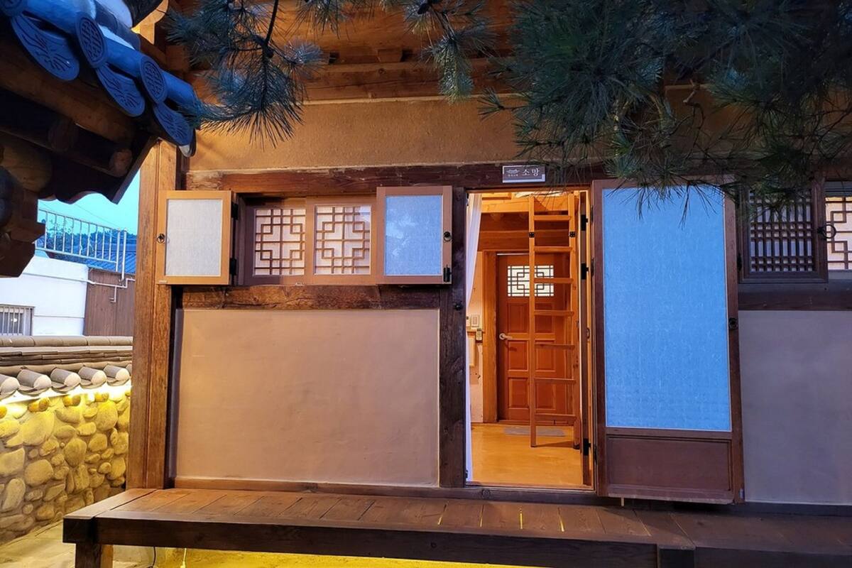 A traditional Japanese building with a wooden exterior, a stone wall, and a wooden door with a lattice design.