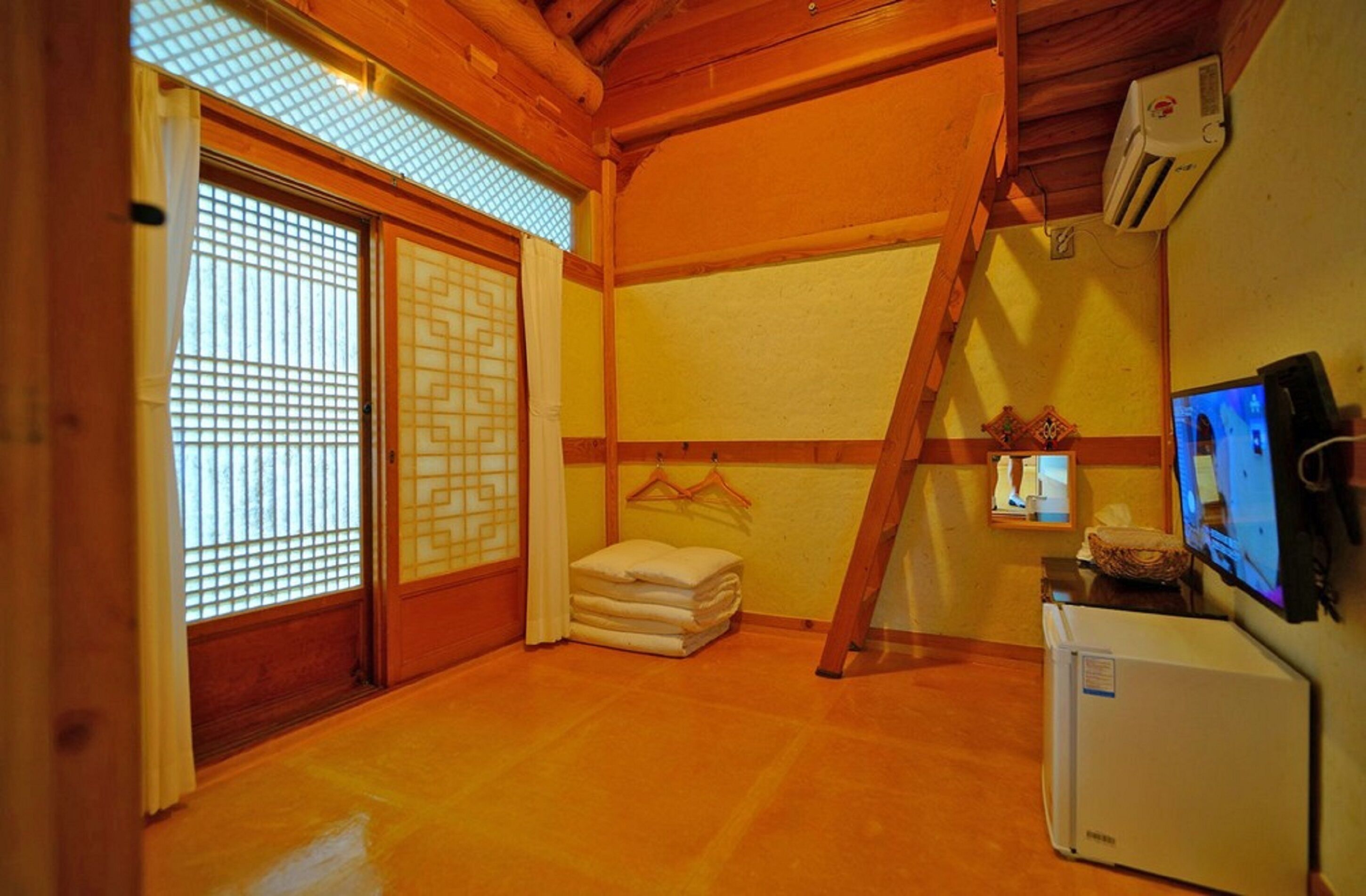 A traditional Japanese room with tatami flooring, a sliding door with a decorative screen, a small heater, and a television on a stand.