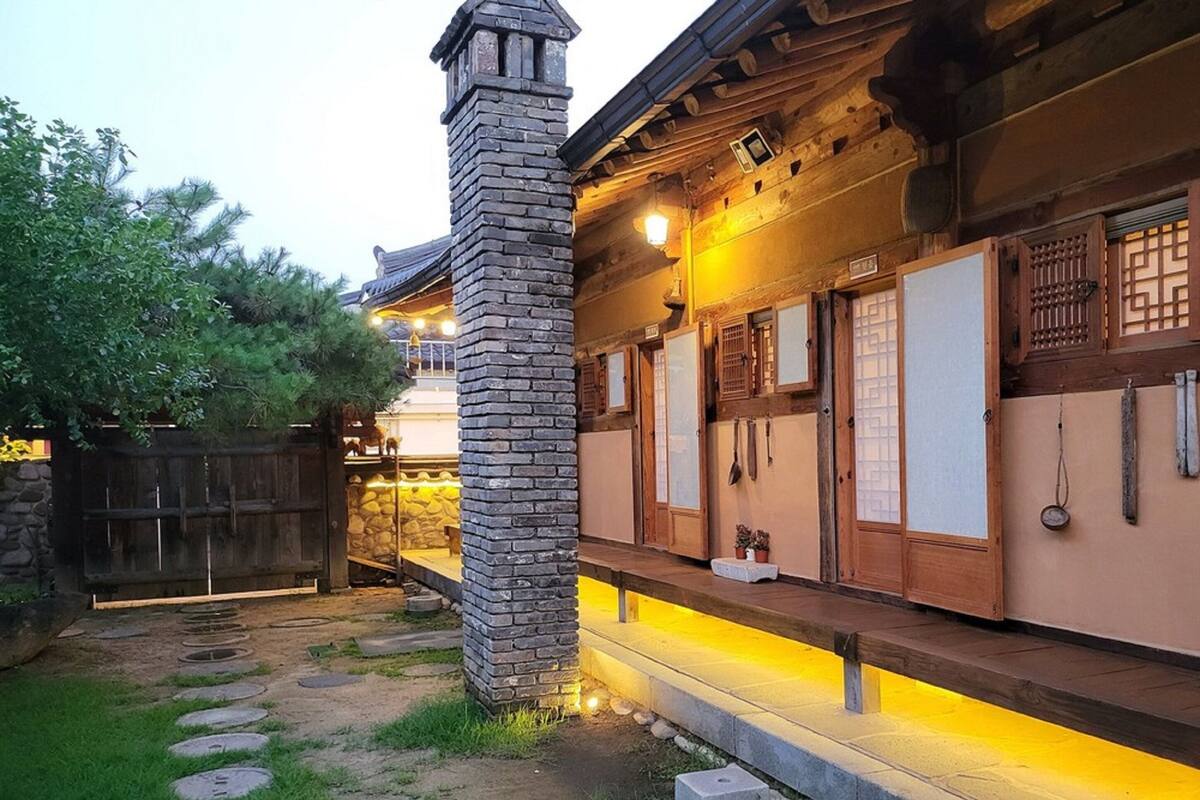 A traditional Japanese building with a stone chimney, wooden doors with sliding panels, and a stone pathway leading to the entrance.