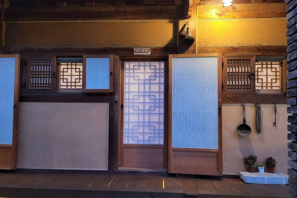 A traditional Japanese building with wooden doors, a shoji screen, and a small garden area with potted plants.