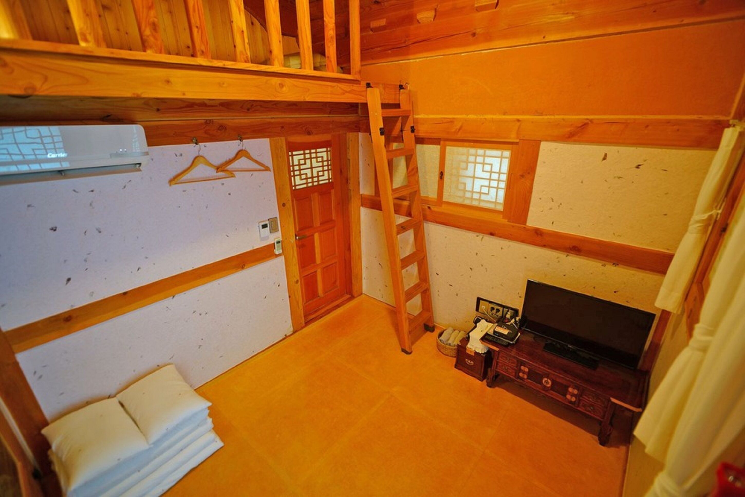A wooden interior with a television, a ladder, and a white towel stack.