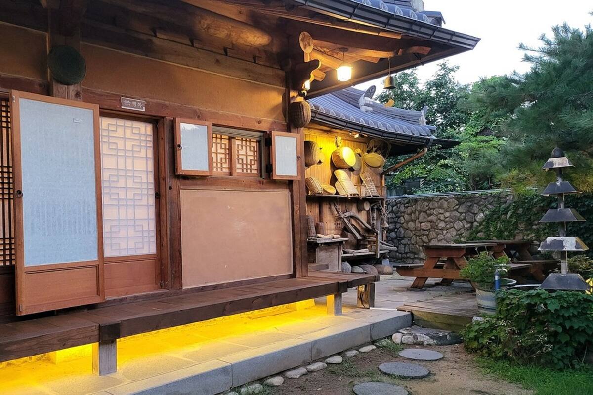 A traditional Japanese building with wooden doors, a stone wall, and a wooden bench.