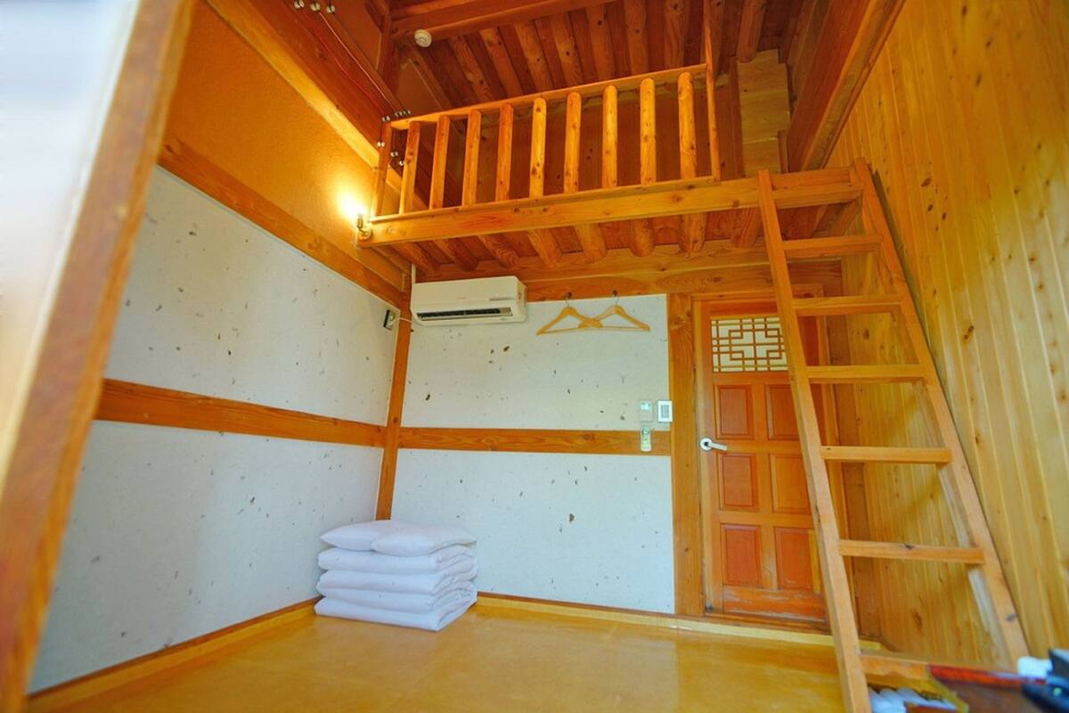 A wooden interior with a balcony, a stack of towels, and a traditional Japanese sliding door.