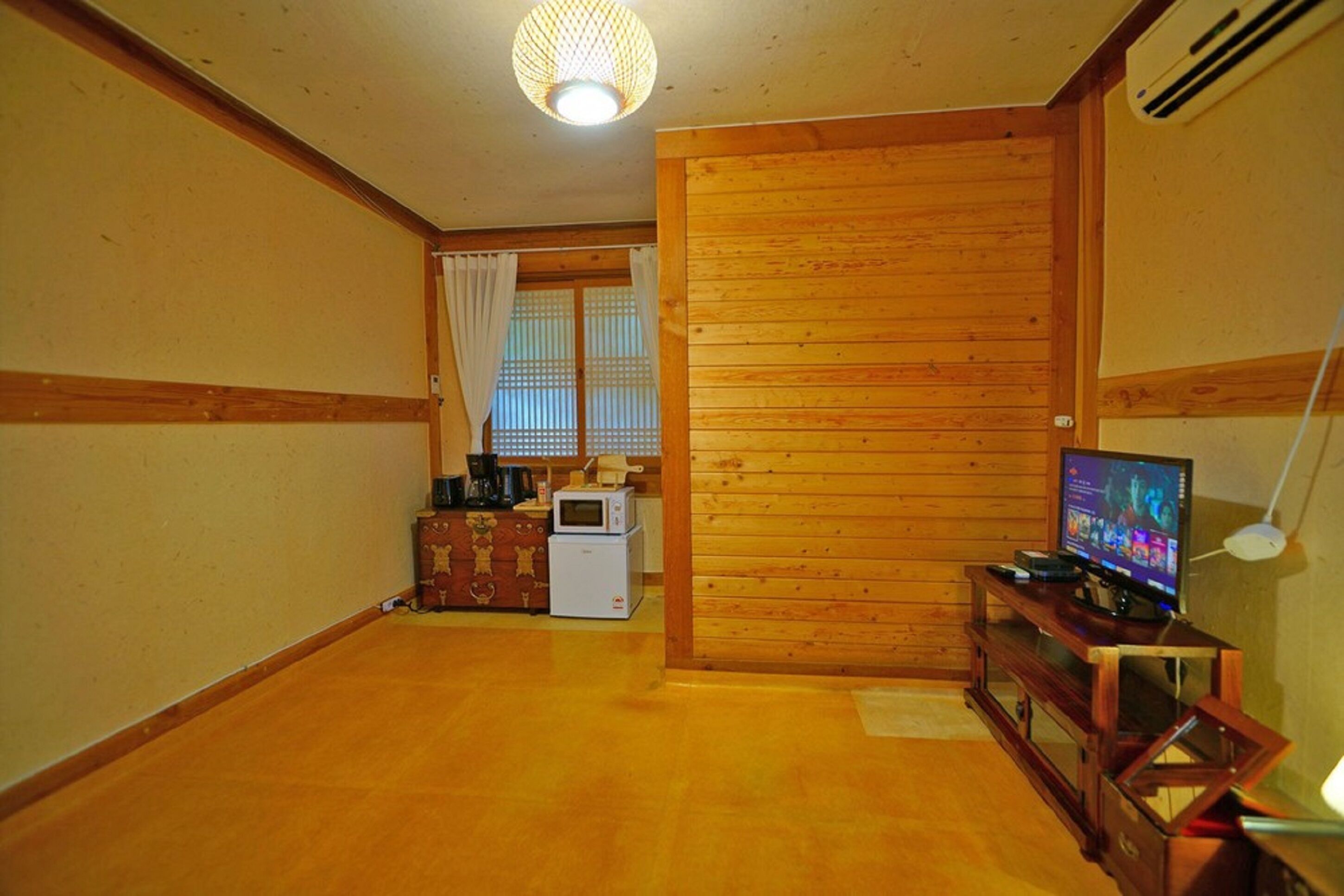 Una sala de estar acogedora con paredes de madera, un televisor, un microondas y una pequeña mesa.