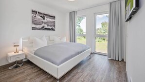Ein modernes Schlafzimmer mit Bett, Nachttisch und einem großen Fenster.