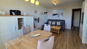 Een moderne woonkamer met een houten eettafel, een bank en een wandtelevisie.