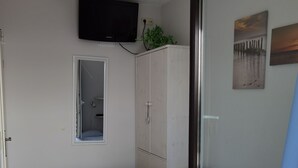 Een slaapkamer met een bed, een kledingkast, een televisie en een raam.