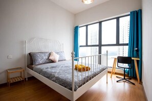 A single bed with a headboard, a bedside table, a chair, and a window with curtains.
