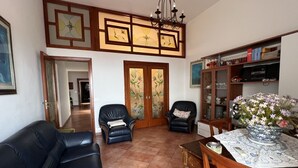 A living room with a sofa, two armchairs, a wooden coffee table, and a cabinet with books and decorative items. - All' Arco - Elegant apartment in the historic center of Fuscaldo (Fuscaldo)