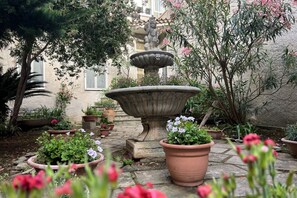 A courtyard with a stone fountain, potted plants, and a building in the background. - All' Arco - Elegant apartment in the historic center of Fuscaldo (Fuscaldo)
