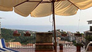 A terrace with a view of the sea, a lounge chair, and potted plants. - All' Arco - Elegant apartment in the historic center of Fuscaldo (Fuscaldo)