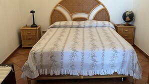 A bed with a floral bedspread, two bedside tables with lamps, and a globe on one of the tables. - All' Arco - Elegant apartment in the historic center of Fuscaldo (Fuscaldo)