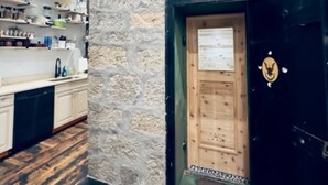A kitchen with wooden cabinets, a stone wall, and a black door with a gold emblem. - The Ruby Peak Condo is part of the historic Litch Hotel (Enterprise)