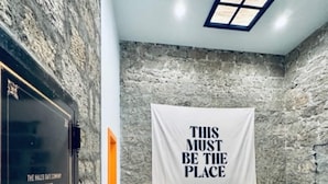 A bedroom with a stone wall, a bed, a nightstand, and a poster on the wall. - The Ruby Peak Condo is part of the historic Litch Hotel (Enterprise)
