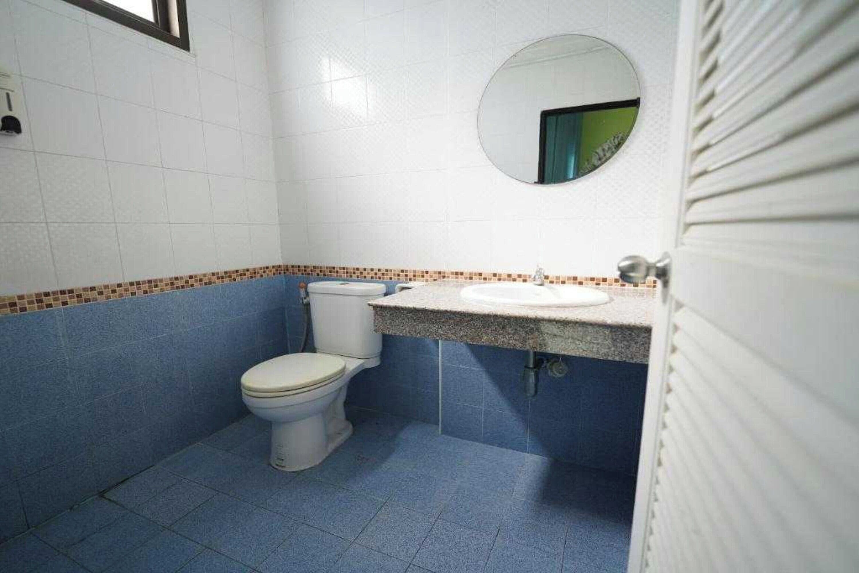 A small bathroom with a toilet, sink, and mirror.