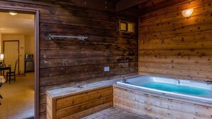 L’intérieur d’un chalet en bois, avec une baignoire en bois et une petite table entourée de chaises.