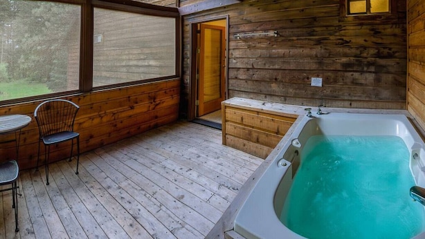 Une cabane avec un intérieur en bois, un jacuzzi et une petite table avec des chaises.