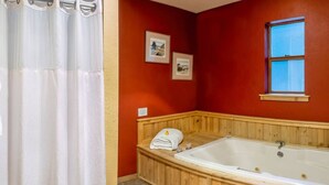 A bathroom with a wooden bathtub, a window, and two framed pictures on the wall. - Lodge Room 5 with Jacuzzi Tub at Green Springs Inn (Ashland)
