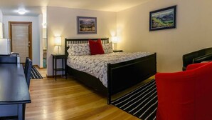 Quarto com cama, mesas de cabeceira, escrivaninha e cadeiras.
