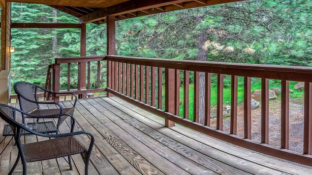 A wooden deck with a railing, two chairs, and a view of a forest. - Lodge Room 6 at Green Springs Inn (Ashland)