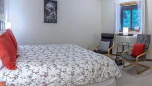 A bedroom with a bed, two chairs, a table, a window with blinds, and a painting on the wall. - Lodge Room 6 at Green Springs Inn (Ashland)