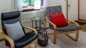 Two chairs with different designs and colors, a small round table, and a wicker basket on a carpeted floor. - Lodge Room 6 at Green Springs Inn (Ashland)