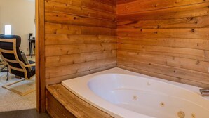 A wooden cabin interior with a large bathtub and a chair. - Lodge Room 4 with Jacuzzi Tub at Green Springs Inn (Ashland)