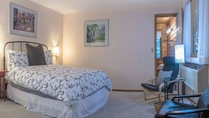 A bedroom with a bed, two chairs, a desk, and a window with blinds. - Lodge Room 4 with Jacuzzi Tub at Green Springs Inn (Ashland)