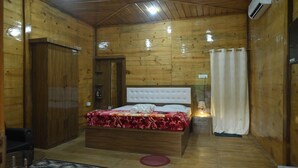 A wooden room with a bed, a wardrobe, and an air conditioning unit. - De Aloha Resort (Tezpur)