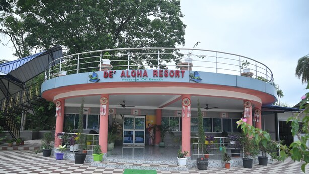 The exterior of De'Aloha Resort with a checkered floor, potted plants, and a signboard. - De Aloha Resort (Tezpur)