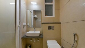 A small, compact bathroom with a white sink, a toilet, and a shower. - Hotel Emporio (Ghaziabad)